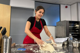 A woman kneading dough smiling.