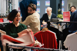 Illustration depicting a shop with a sale on, and a man and woman grabbing clothing items with an excited face.