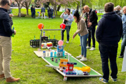 A picture showing a group of people playing a mini gold hole made out of non-perishable items