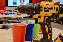 A close up image of a drill and coloured cups of nails.