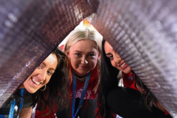 A picture showing 3 woman peering through one side of a sleeping pod.